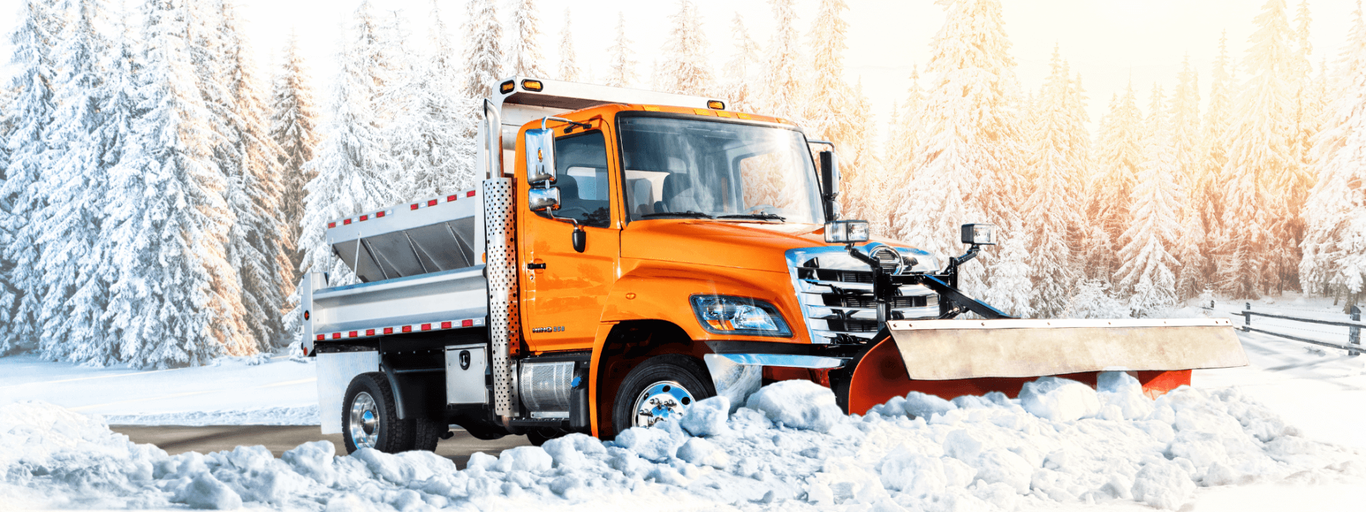 Orange Hino truck scooping snow